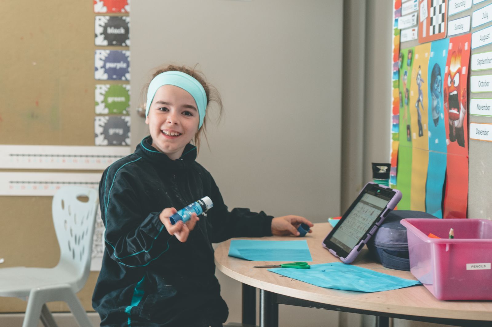 Student gluing her schoolwork and smiling at the camera